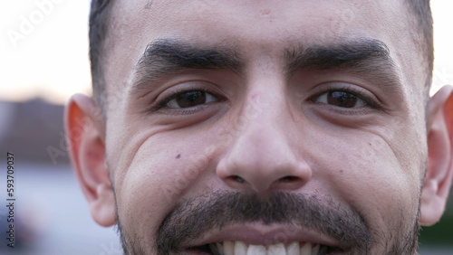One Middle Eastern young man close up face and eyes smiling at camera. An Arab 20s male person with wrinkles