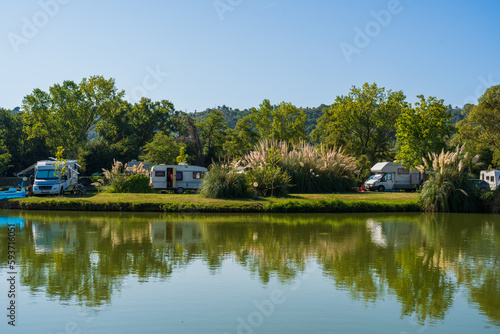 Motorhomes and bicycles on the lake by the river with camping tables, sport fishing and cycling for relaxation, summer travel and outdoor recreation, authentic sustainability, natural beauty of nature