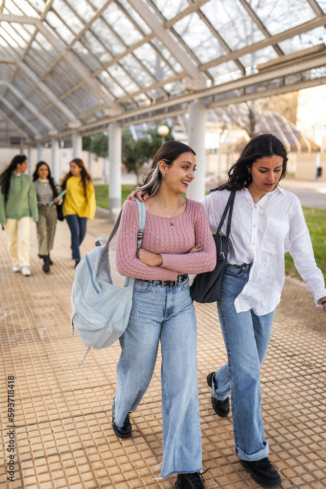 female student friends walking through university campus female student friends walking through university campus