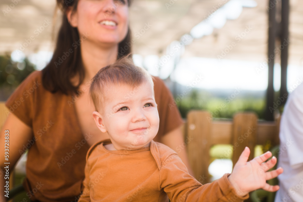 Smiling baby waving with funny face on mother legs Smiling baby waving with funny face on mother legs