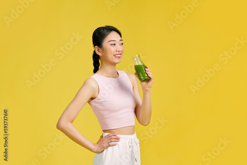 Portrait of young smiling millenial woman drinking green smoothie photo