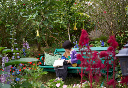 Asian little boy drawing peacefully on a bench in a beautiful garden
