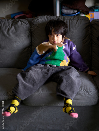 Asian little boy sulking lying on sofa photo