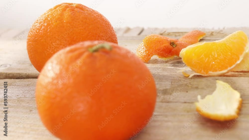 oranges on a wooden table. citruses with peeled peel and slices on a light background. fruit under sunlight oranges on a wooden table. citruses with peeled peel and slices on a light background. fruit under sunlight