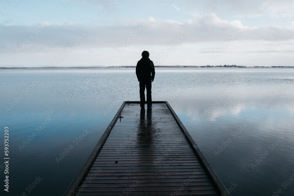 Young man looks out over cold lake in Iceland Young man looks out over cold lake in Iceland