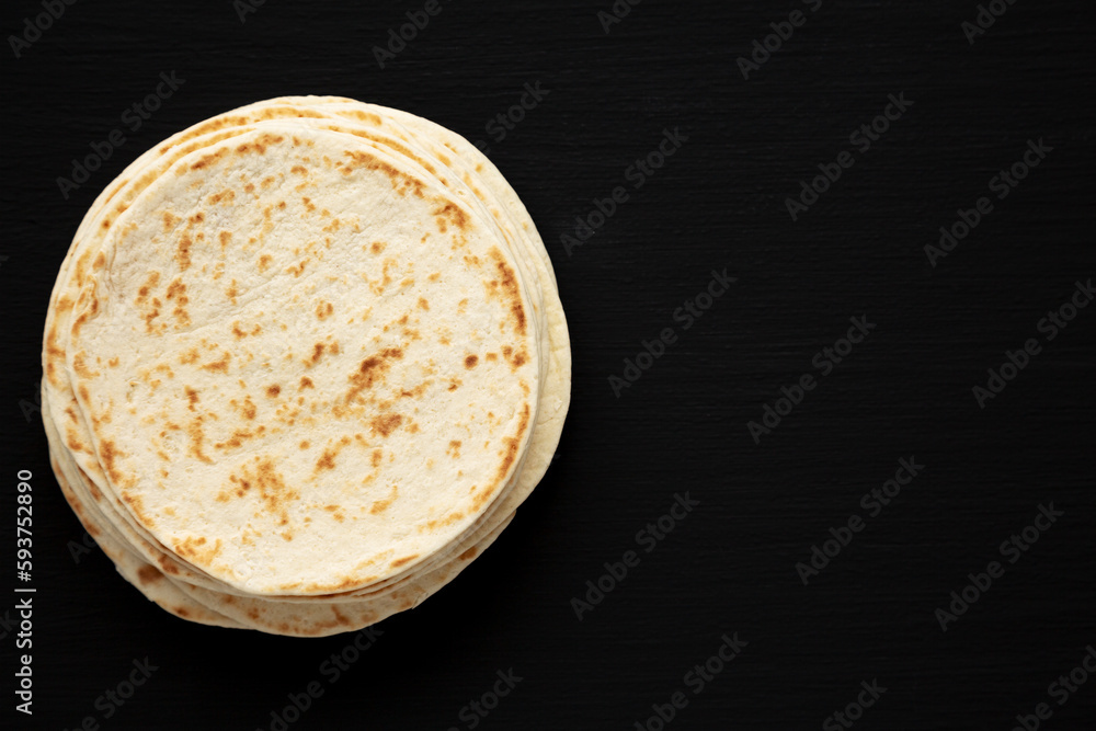 Stack of Whole Wheat Flour Tortillas on a black background, top view. Flat lay, overhead, from above. Copy space. Stack of Whole Wheat Flour Tortillas on a black background, top view. Flat lay, overhead, from above. Copy space.