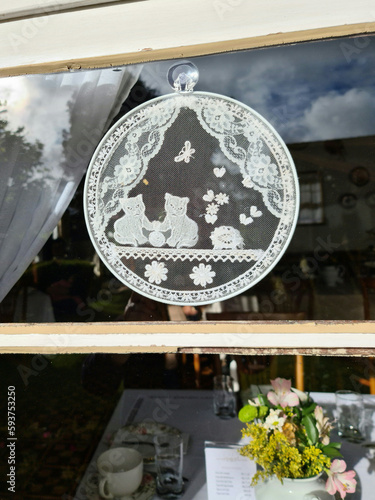 bucolic landscape window with bobbin lace and table with flowers plates and cutlery in the background
