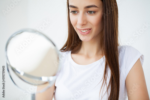 Young woman applying makeup on face at home