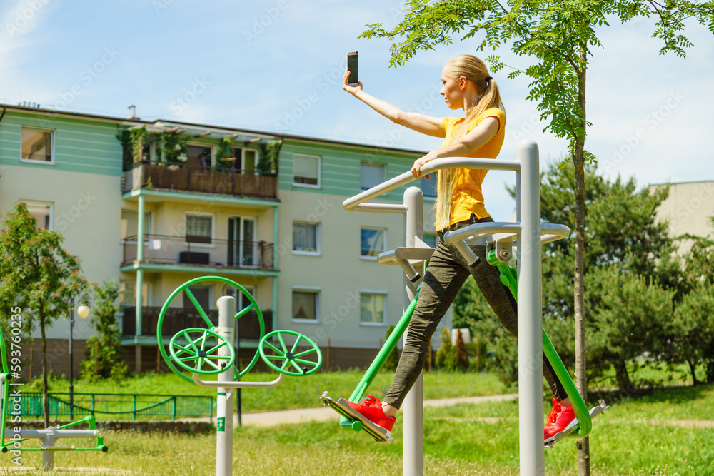 Fototapeta premium Girl doing exercises outdoor, taking selfie