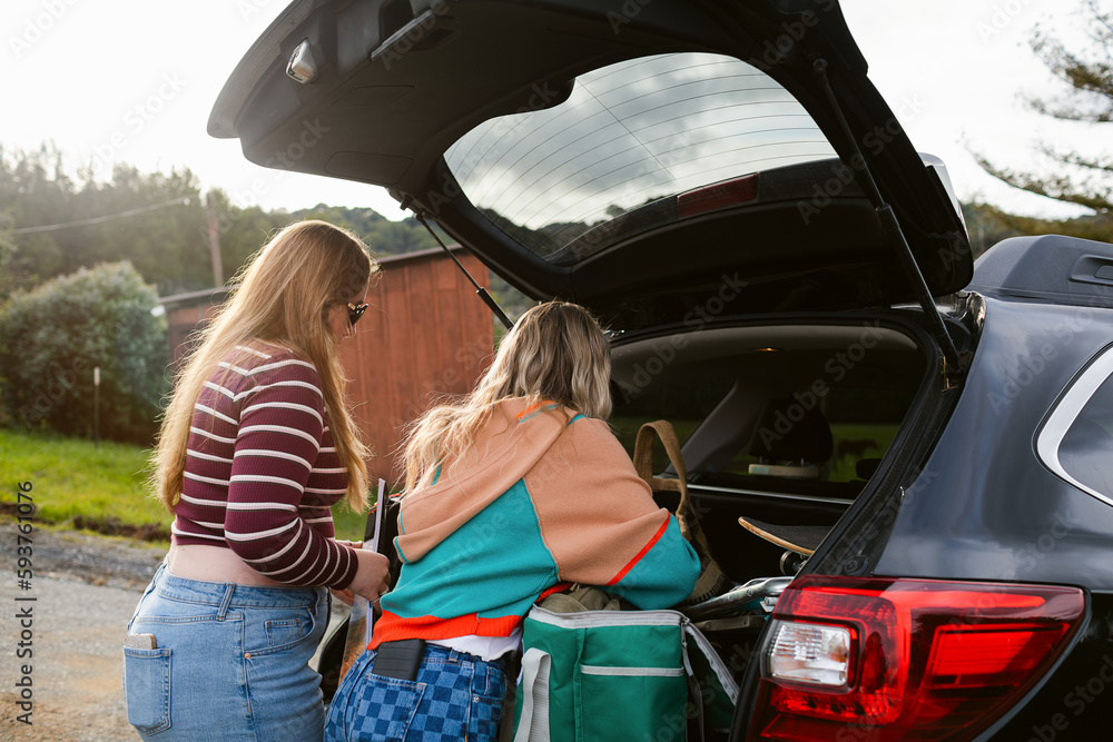 Teenage girls stow away their road trip luggage Teenage girls stow away their road trip luggage