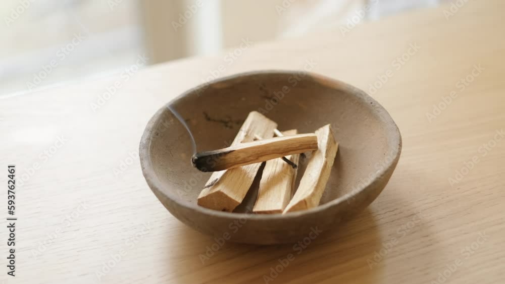 Healing incense Palo Santo sticks on light background. Organic incense of holy ritual tree incense in clay bowl on wooden table in minimalist interior. Ibiokai. Wellness with aromatherapy and occult. Healing incense Palo Santo sticks on light background. Organic incense of holy ritual tree incense in clay bowl on wooden table in minimalist interior. Ibiokai. Wellness with aromatherapy and occult.