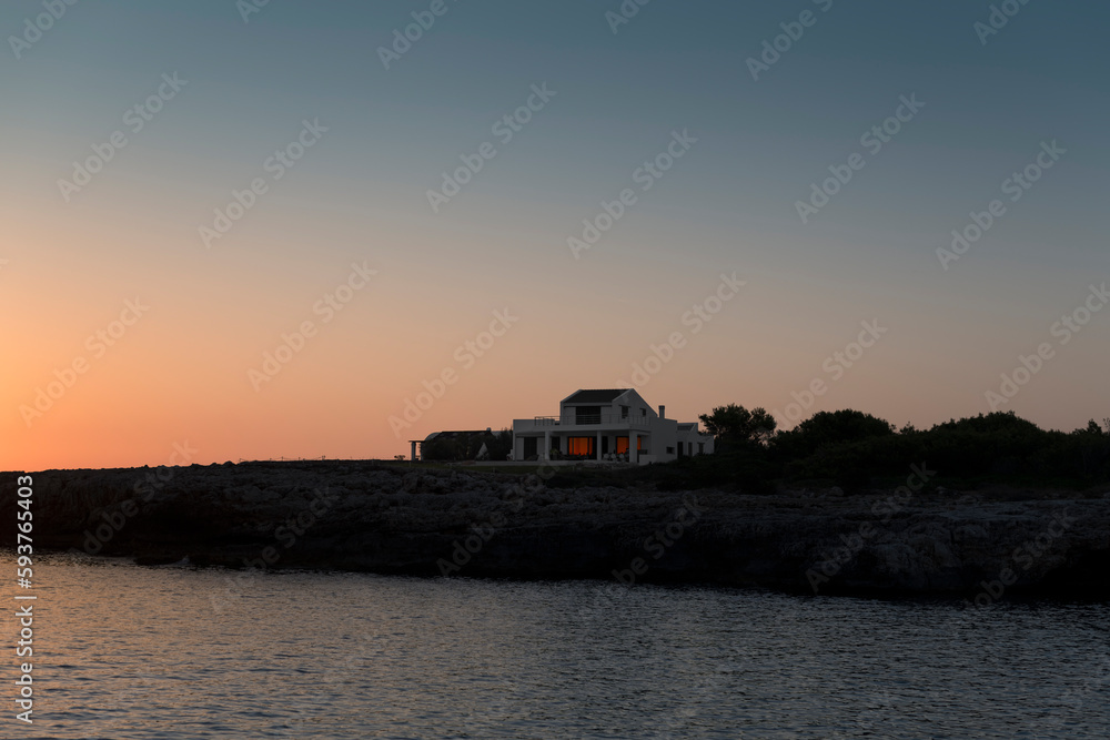 © Ibai Acevedo/Stocksy - Scenic house next to cliff and sea during sunset © Ibai Acevedo/Stocksy - Scenic house next to cliff and sea during sunset