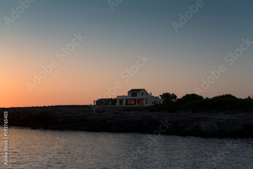 Scenic house next to cliff and sea during sunset photo