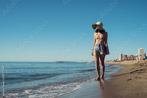 young beautiful girl freelancer with a laptop walks on the seashore