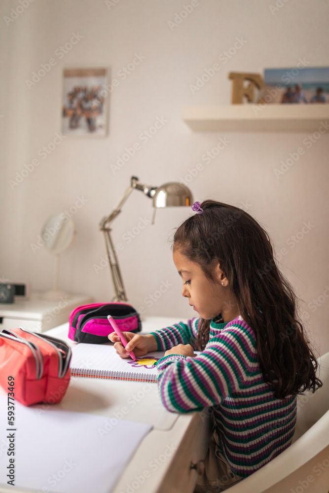 Concentrated little artist drawing at her desk in the room Concentrated little artist drawing at her desk in the room