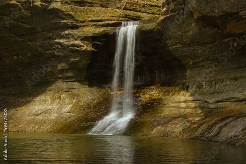 A slower shutter-speed smooths the flow of a waterfall from a rocky cliff into a calm pond inside a rocky canyon at Matthiessen State Park  near Oglesby  IL.