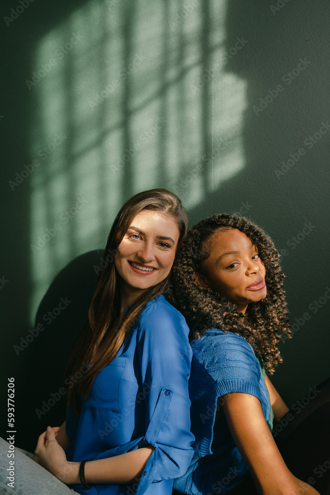 close up of two friends back to back smiling close up of two friends back to back smiling