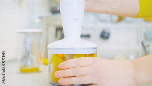 In a kitchen, a young woman prepares a healthy smoothie using a blender. Surrounding her are fresh fruits, including sliced pineapple on a wooden cutting board. nutrition and healthy eating.