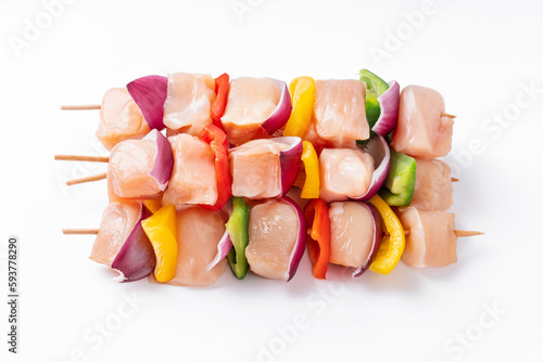 Raw chicken skewers with vegetables, peppers, onions, on a white background.Uncooked mixed meat skewer with peppers.Skewers with pieces of raw meat, red, yellow and green pepper.Top view.