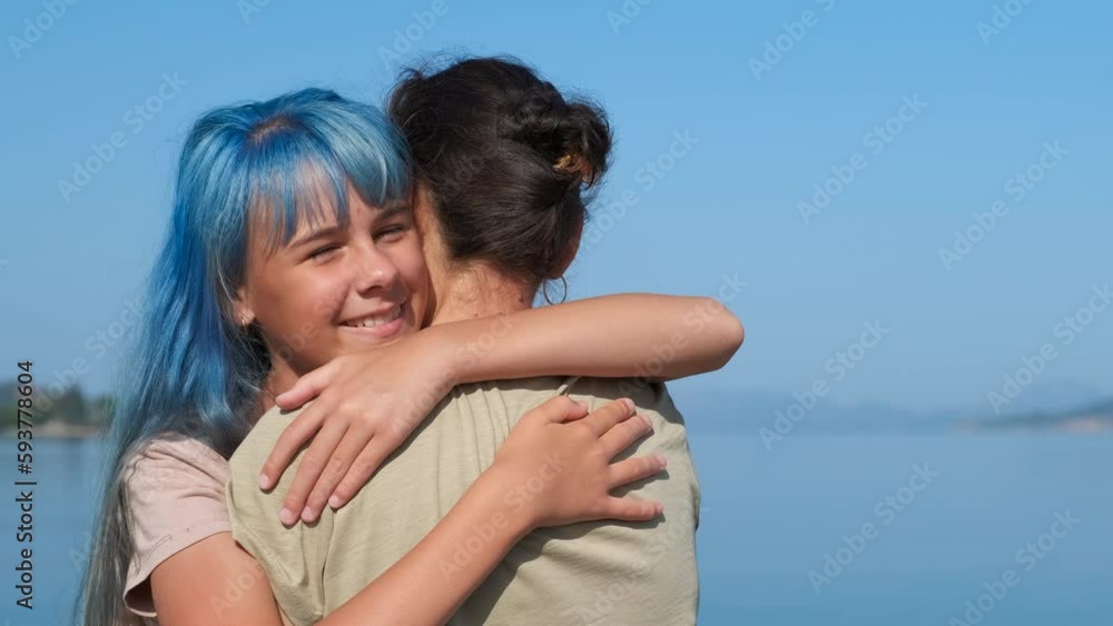 Love mother against seascape. A mother with love embrace her daughter with blue hair against seascape under sun. Love mother against seascape. A mother with love embrace her daughter with blue hair against seascape under sun.