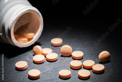 An overturned bottle of pills on a black table. Gloomy lighting. Depression concept. Close-up. Space for text.