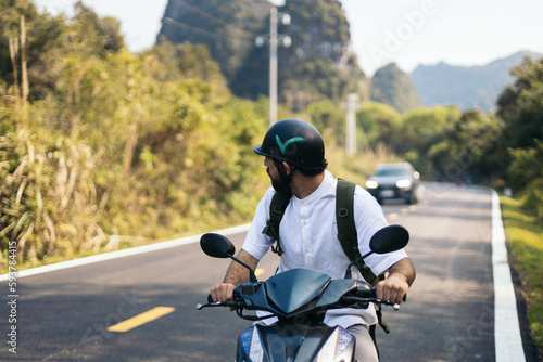 Traveler driving a scooter in the nature of Southeast Asia photo