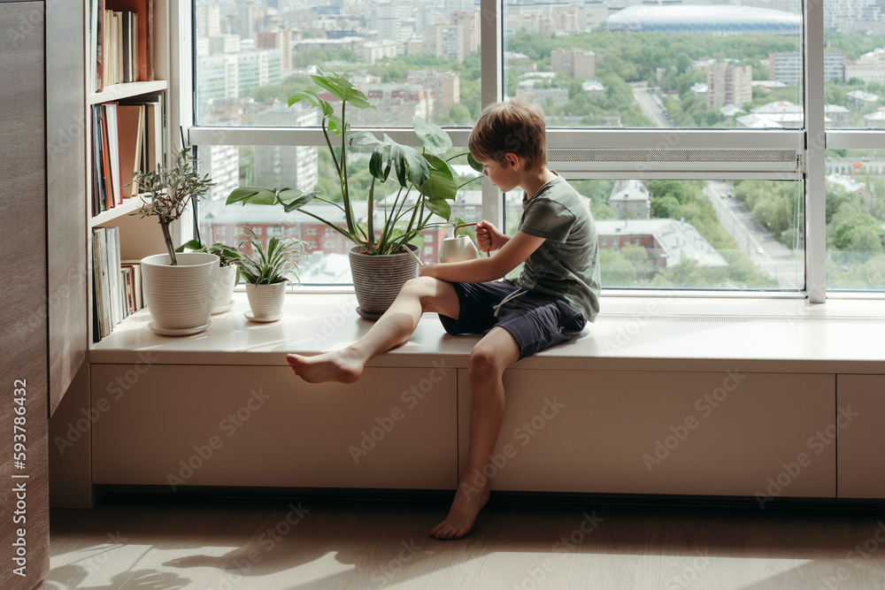 Kid takes care of green plants at home. Kid takes care of green plants at home.