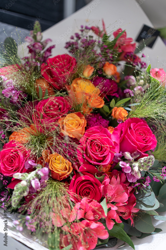 Pink, red and orange roses with green grass in a bouquet in red tones Pink, red and orange roses with green grass in a bouquet in red tones