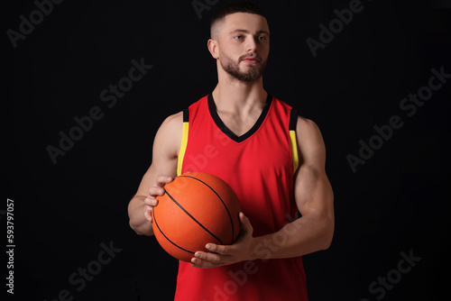 Athletic young man with basketball ball on black background © New Africa