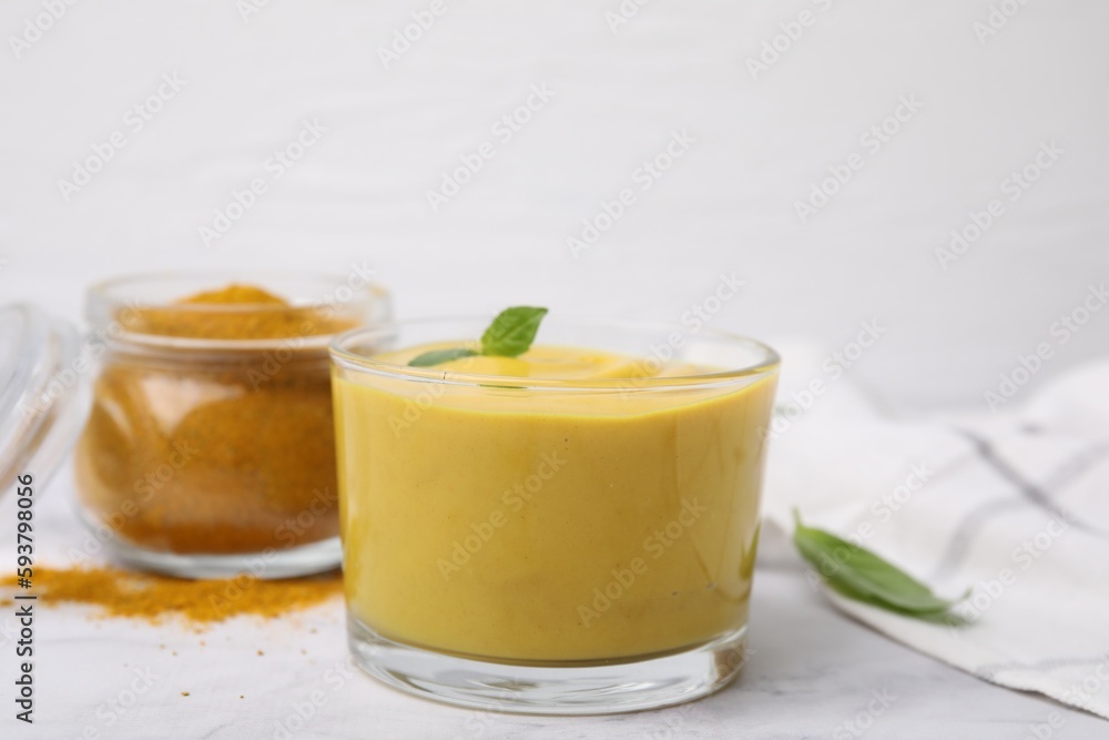 Tasty curry sauce, powder and basil leaves on white table, closeup Tasty curry sauce, powder and basil leaves on white table, closeup