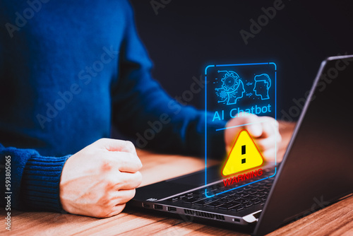 Young man using laptop chatting with a smart AI using an artificial intelligence chatbot with triangle caution warning sign for notification error concept. Chat with AI, Artificial Intelligence.