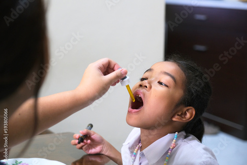 Asian little girl having drops medicine photo