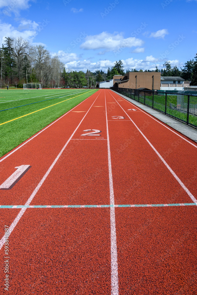 Four lane artificial sports track around an artificial turf soccer and football field, sunny spring day
