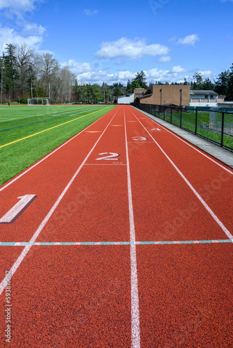 Four lane artificial sports track around an artificial turf soccer and football field, sunny spring day 