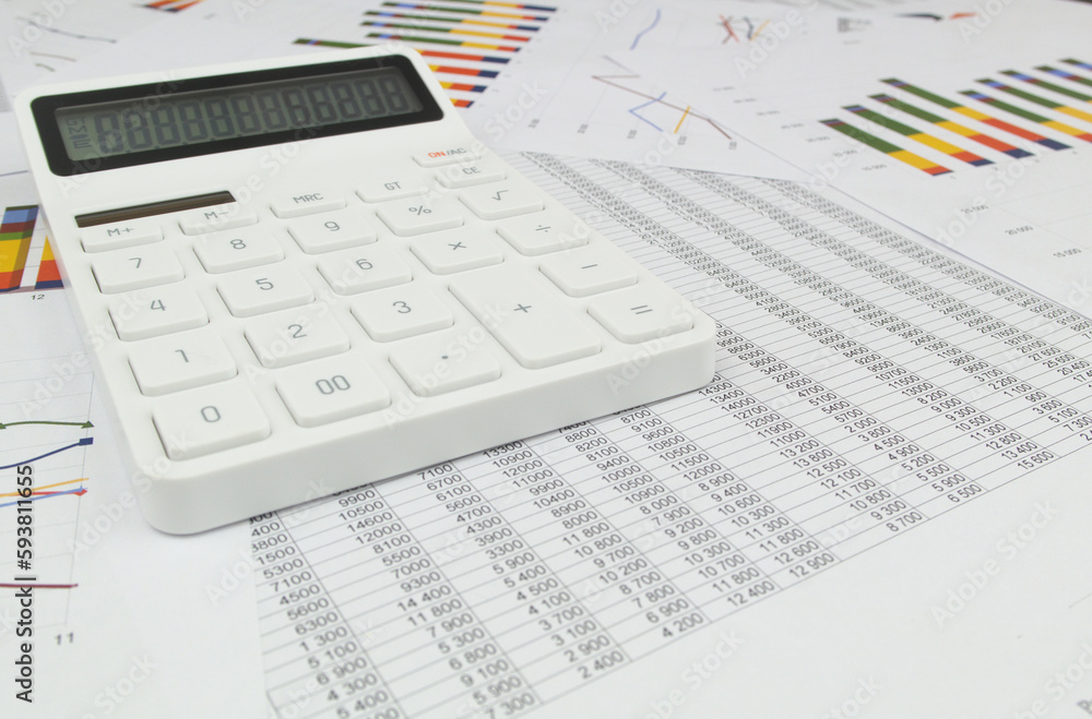 Wide angle image of white calculator on documents with charts and numbers. Wide angle image of white calculator on documents with charts and numbers.