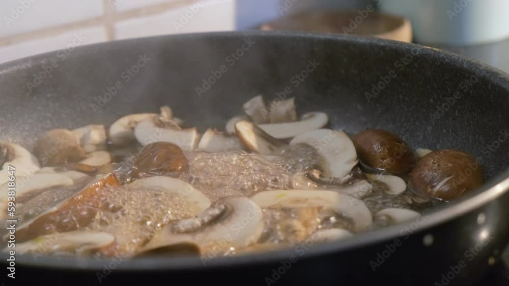 Close up of fresh sliced mushrooms cooking in a pan for a delicious healthy recipe Close up of fresh sliced mushrooms cooking in a pan for a delicious healthy recipe