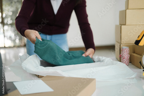 Businesswoman folding clothes for online order.