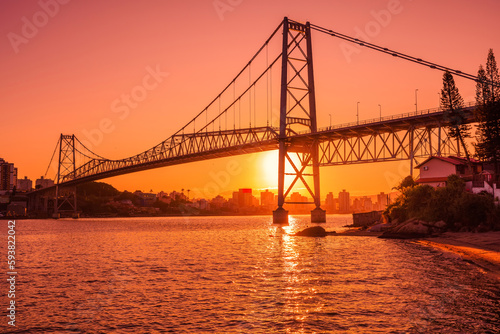 Hercilio luz bridge with warm sunset and reflection on water in Florianopolis © artifirsov