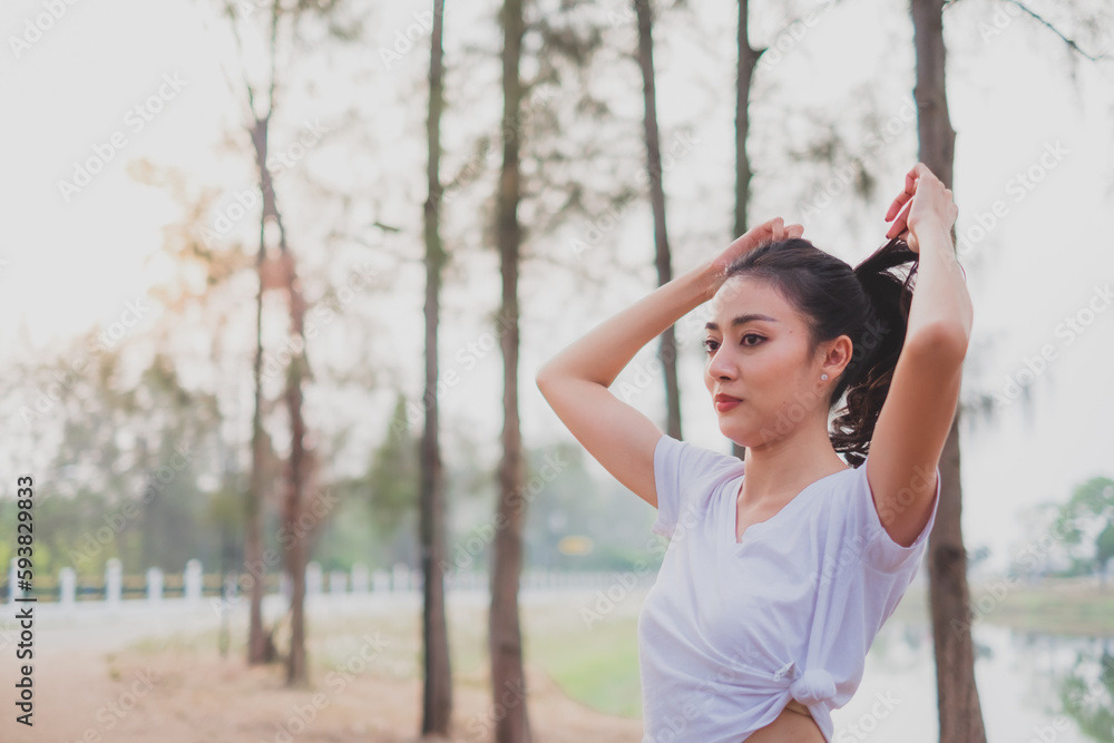Young woman tied her hair before practicing exercise, doing stretching out before running or jogging. Concept of healthy life, relaxation ,recreation. City life style. Body movement. warm up Young woman tied her hair before practicing exercise, doing stretching out before running or jogging. Concept of healthy life, relaxation ,recreation. City life style. Body movement. warm up