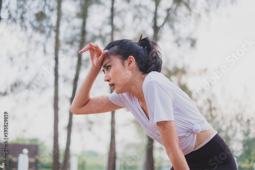 Murais de parede An Asian woman is exhausted and wipe sweat after running, jogger, work out or do morning exercising