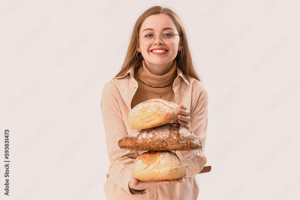 Young woman with loaves of fresh bread on light background Young woman with loaves of fresh bread on light background