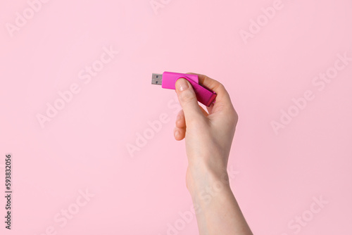 Woman holding USB flash drive on pink background