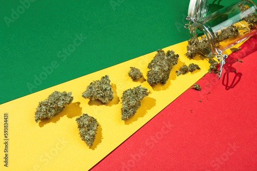 Quadro su tela On a rasta background lie dry buds of medical marijuana pouring out of a glass j