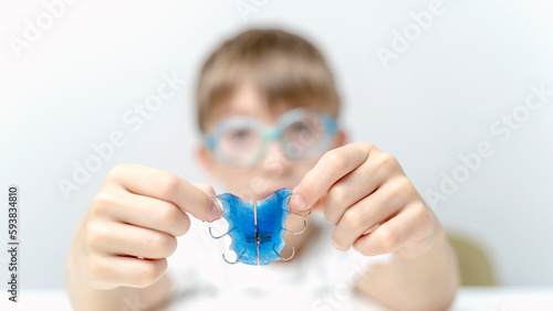 Dental plate. Expansion of the jaw in a child. A plate to heaven. There is not enough room for the molars. Happy girl holding an orthodontic plate in her hands