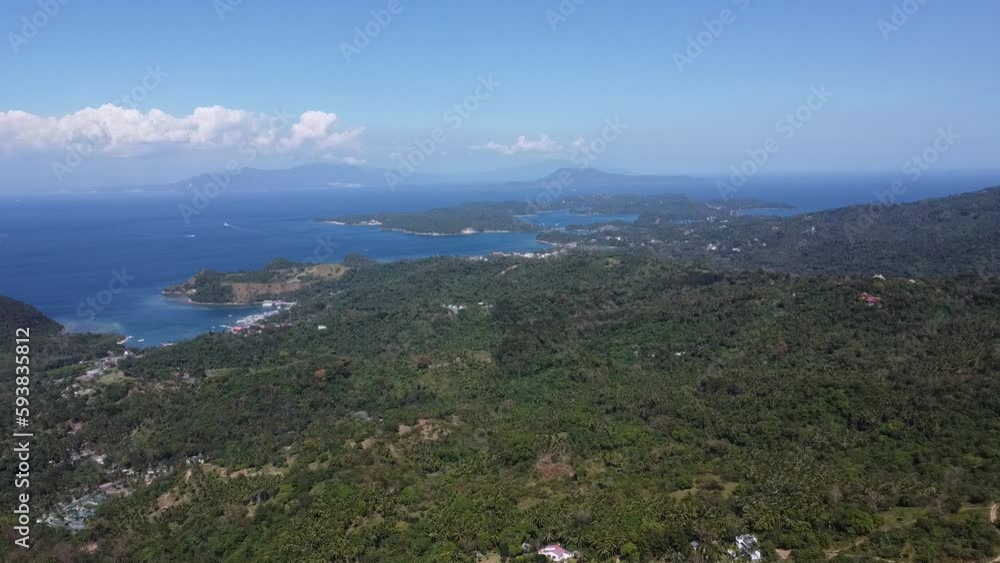 Aerial view of mountains and sea on a tropical island. The mountains and hills are covered with tropical rainforest. Small settlements on the island among the jungle. Aerial view of mountains and sea on a tropical island. The mountains and hills are covered with tropical rainforest. Small settlements on the island among the jungle.