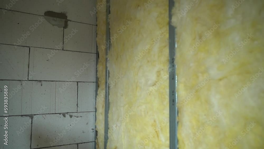 A frame made of galvanized metal beams for drywall holds yellow glass wool. Heat and sound insulation of the wall between the rooms A frame made of galvanized metal beams for drywall holds yellow glass wool. Heat and sound insulation of the wall between the rooms