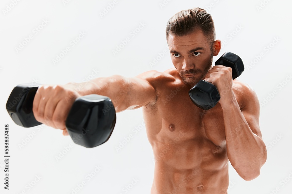 Man athletic body bodybuilder posing with dumbbells with naked torso abs full-length in the background, fitness class. Advertising, sports, active lifestyle, competition, challenge concept. 