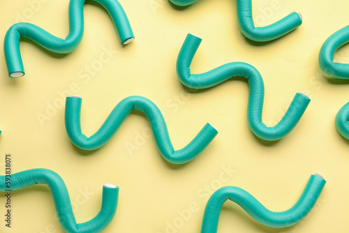 Hair curlers on yellow background, closeup