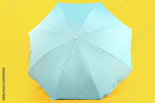 Blue beach umbrella on yellow background
