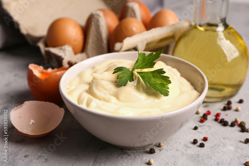 Bowl with tasty mayonnaise sauce on grunge background, closeup